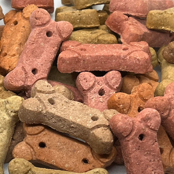 A close up of a pile of red, green, brown and orange bone shaped cbd dog treats.