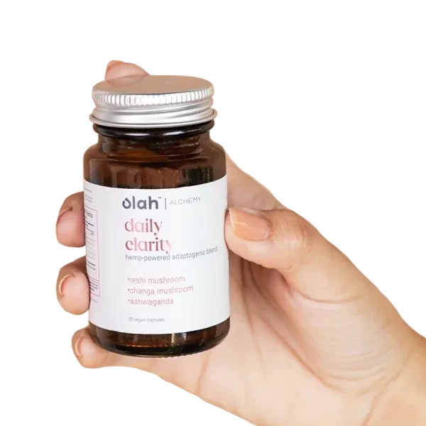 Hand holds bottle of olah daily clarity hemp powered adaptogenic blend made with reshi mushroom, changa mushroom, and ashwagandha