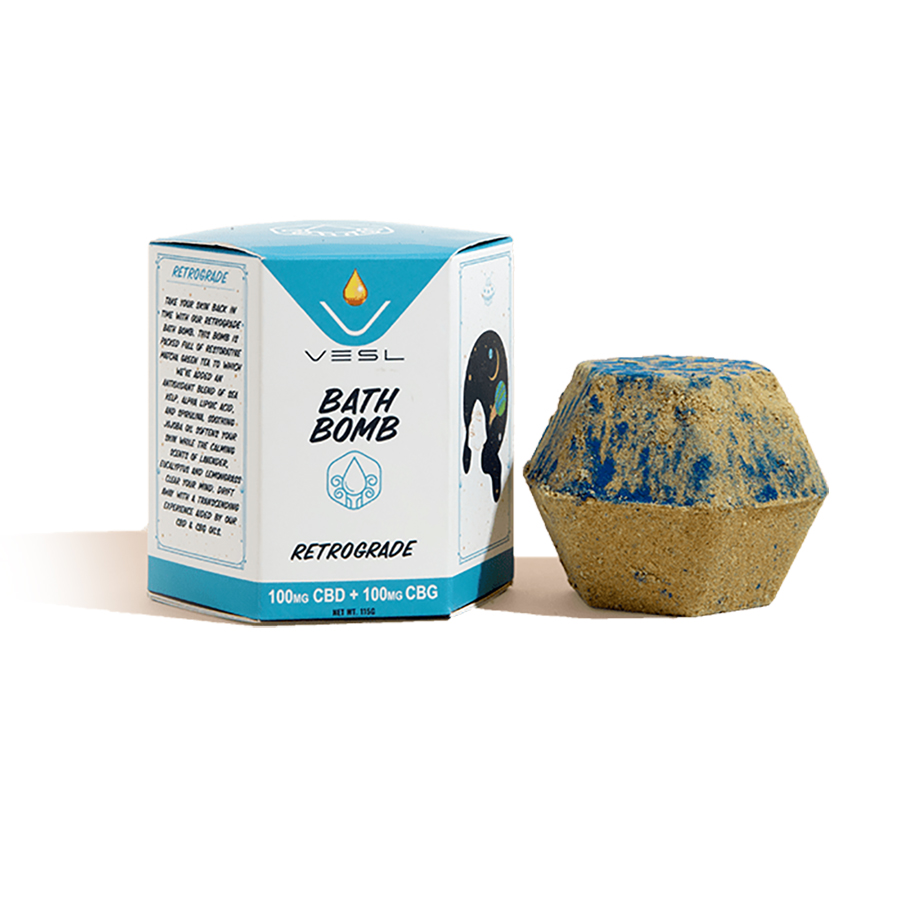 Vesl brand Retrograde CBD CBG Bath Bomb packaging next to sandy tan and blue bath bomb